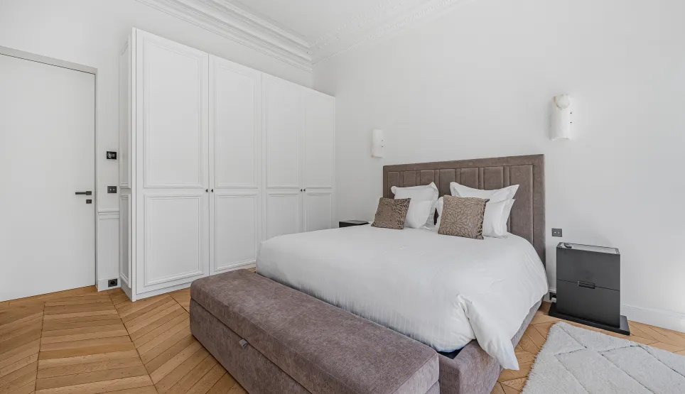 Chambre de luxe contemporaine, design épuré. Lit confortable, dressing intégré, parquet. Ambiance lumineuse et élégante.