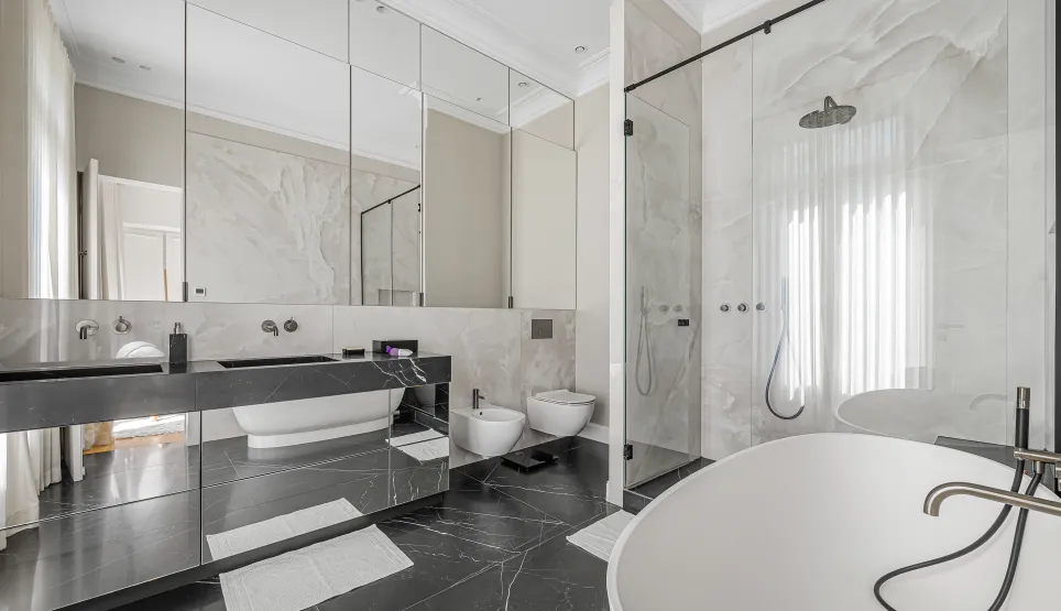Salle de bain de luxe moderne avec marbre noir et blanc, double vasque, baignoire îlot et douche à l'italienne. Design élégant et haut de gamme.