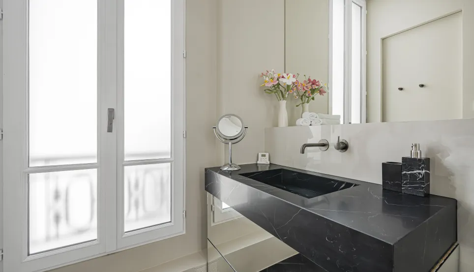 Salle de bain de luxe avec lavabo en marbre noir, design moderne et élégant. Ambiance raffinée, fenêtre lumineuse.