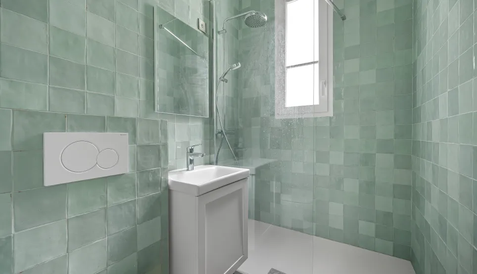 Salle de bain contemporaine avec douche à l'italienne, carrelage vert d'eau lumineux. Design épuré pour un intérieur de luxe moderne.