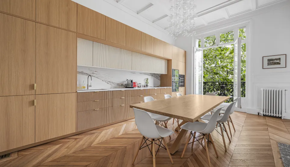 Cuisine salle à manger de luxe, design moderne et élégant. Parquet, boiseries sur mesure, marbre, vue verdoyante. Appartement parisien.