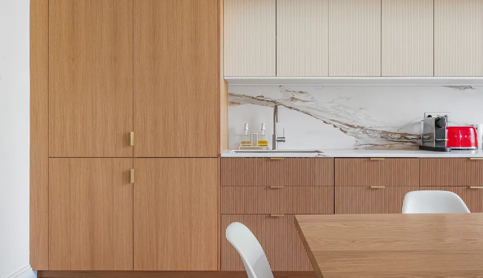 Cuisine design luxe: bois clair, marbre veiné, finitions dorées. Aménagement contemporain avec parquet chevrons et électroménager Smeg.
