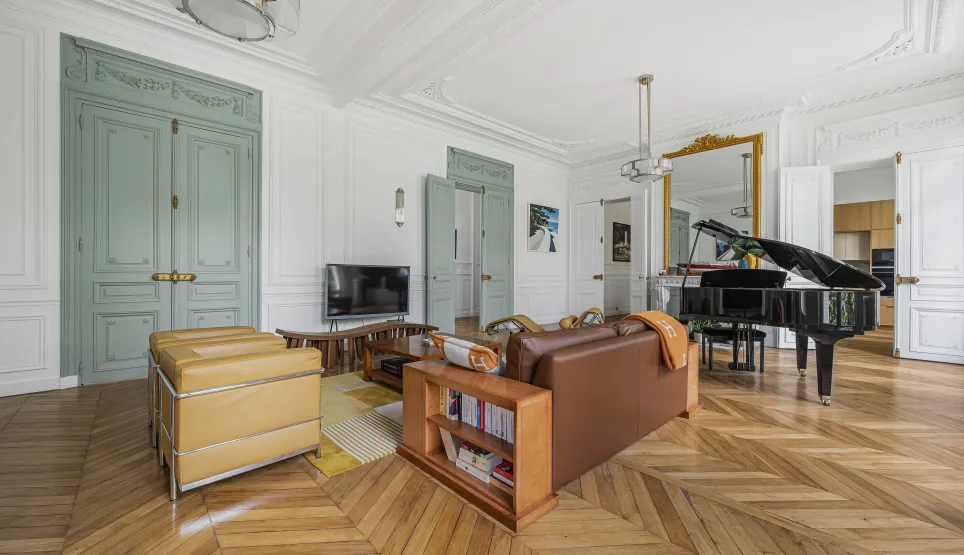 Salon de luxe parisien, parquet chevrons, moulures, piano à queue. Design élégant et raffiné pour appartement haussmannien.