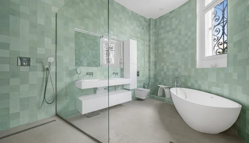 Salle de bain de luxe avec carrelage zellige vert d'eau, baignoire îlot contemporaine, douche à l'italienne et double vasque flottante.