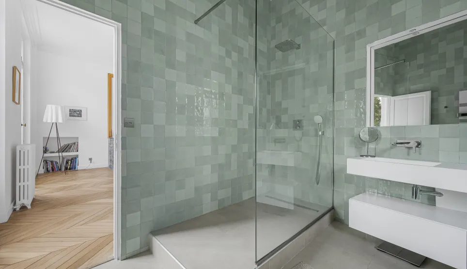 Salle de bain de luxe moderne avec douche à l'italienne et carrelage zellige vert d'eau. Design élégant pour un appartement haut de gamme.