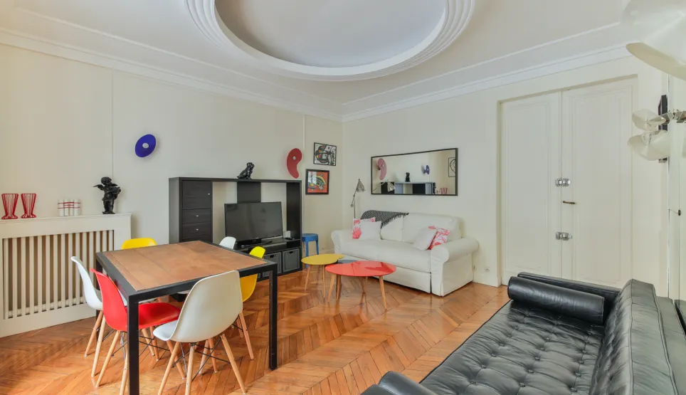 Luxueux salon-salle à manger moderne. Parquet, mobilier design coloré, espace lumineux. Idéal pour un appartement de prestige.