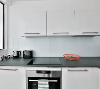 Cuisine moderne blanche et épurée avec électroménager intégré, plan de travail foncé. Idéal pour appartement de luxe.