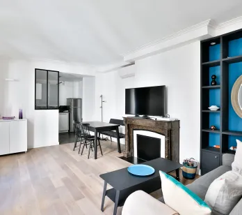 Salon moderne lumineux avec cuisine ouverte, cheminée, rangements intégrés bleus. Design contemporain pour appartement de luxe.