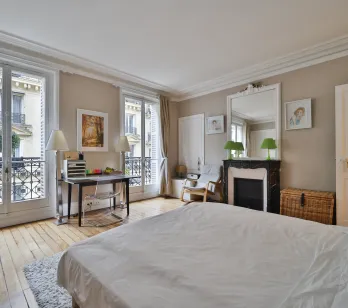 Chambre luxe Haussmannienne avec balcon, parquet, cheminée marbre. Suite élégante, bureau, moulures. Appartement parisien de prestige.