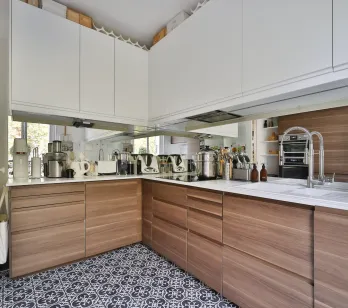 Cuisine de luxe moderne bois/blanc, carrelage design. Électroménager intégré, miroir mural. Espace fonctionnel et élégant pour vie contemporaine.