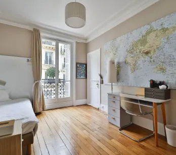 Chambre/bureau parisien lumineux, parquet, balcon, carte du monde. Design moderne et élégance classique pour un intérieur de luxe.