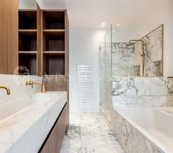 Salle de bain de luxe moderne : marbre blanc, double vasque, robinetterie dorée, douche à l'italienne et baignoire. Design élégant.