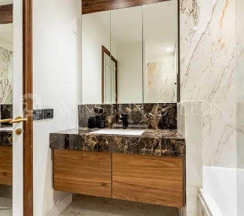 Salle de bain de luxe moderne. Marbre veiné clair et foncé, meuble vasque en bois élégant et grand miroir. Design intérieur haut de gamme.