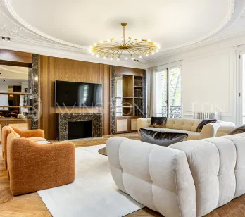 Superbe salon de luxe: design moderne, cheminée marbre, parquet, moulures, canapés design. Ambiance lumineuse et raffinée pour appartement parisien.