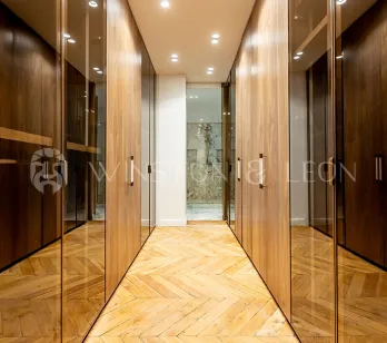 Dressing de luxe moderne avec placards en bois et verre, parquet chevrons. Rangement élégant pour propriété haut de gamme.
