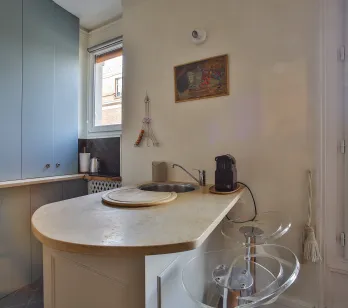 Cuisine moderne et élégante avec îlot/bar, vue imprenable sur les toits de Paris. Appartement de luxe parisien, design contemporain.