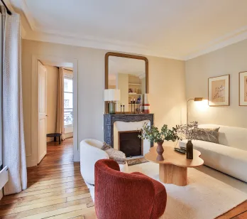 Salon parisien luxe, design moderne et élégant avec cheminée, parquet et lumière naturelle. Idéal pour un appartement haut de gamme.