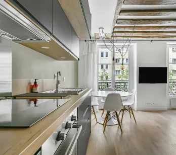 Appartement de luxe: cuisine moderne ouverte sur séjour lumineux, poutres apparentes, parquet. Élégance parisienne.