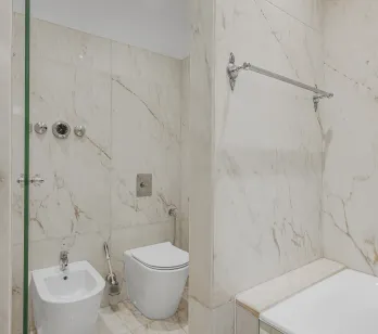 Salle de bain de luxe en marbre avec douche, baignoire, WC et bidet. Design élégant et finitions haut de gamme.