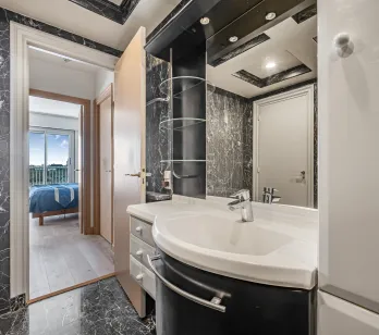 Salle de bain élégante en marbre noir, design moderne avec vasque intégrée. Accès suite parentale lumineuse avec vue. Luxe et confort.