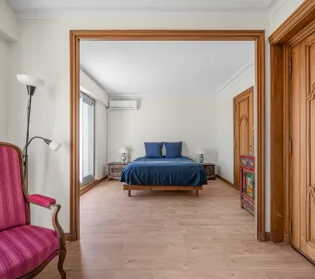 Suite parentale lumineuse et élégante avec lit double bleu, parquet bois clair et mobilier raffiné. Un intérieur de charme pour propriété de luxe.