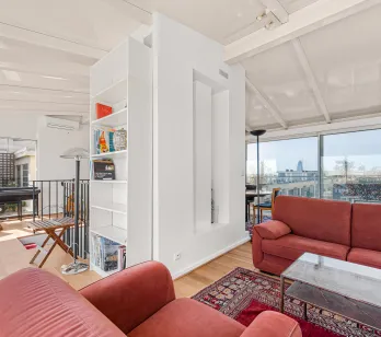 Penthouse de luxe : salon moderne et lumineux avec vue panoramique sur la ville, grandes baies vitrées et accès terrasse. Design contemporain.