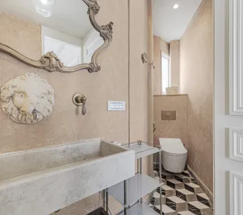 Luxueuse salle d'eau: miroir baroque, lavabo pierre, robinet tête de lion. Design élégant, carrelage géométrique. Intérieur chic et raffiné.