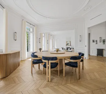 Salle à manger de luxe lumineuse, design élégant. Appartement parisien avec parquet chevrons, moulures. Raffinement et espace.