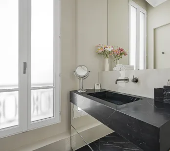 Salle de bain de luxe avec lavabo en marbre noir, design moderne et élégant. Ambiance raffinée, fenêtre lumineuse.