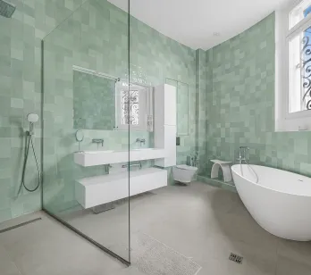 Salle de bain de luxe avec carrelage zellige vert d'eau, baignoire îlot contemporaine, douche à l'italienne et double vasque flottante.