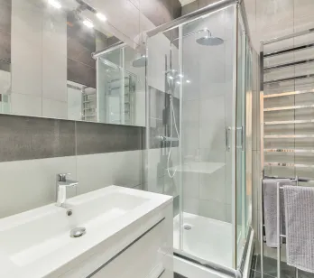 Salle de bain moderne et élégante avec douche vitrée, vasque design et sèche-serviettes chromé. Finitions haut de gamme pour un confort optimal.