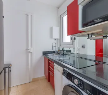 Cuisine moderne et élégante, entièrement équipée (lave-linge, micro-ondes), design contemporain rouge et noir. Idéal pour appartement de luxe.