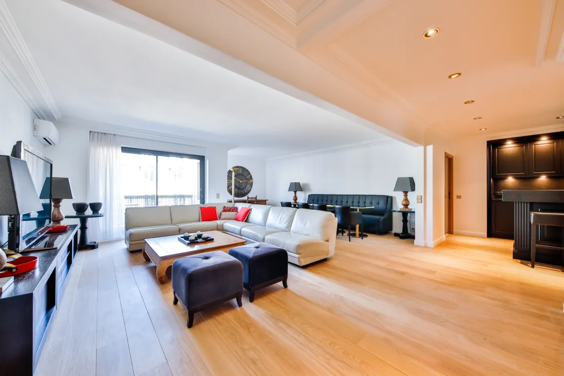 Salon de luxe spacieux et lumineux avec parquet clair, canapé sectionnel moderne, coin repas et bar intégré. Design contemporain haut de gamme.