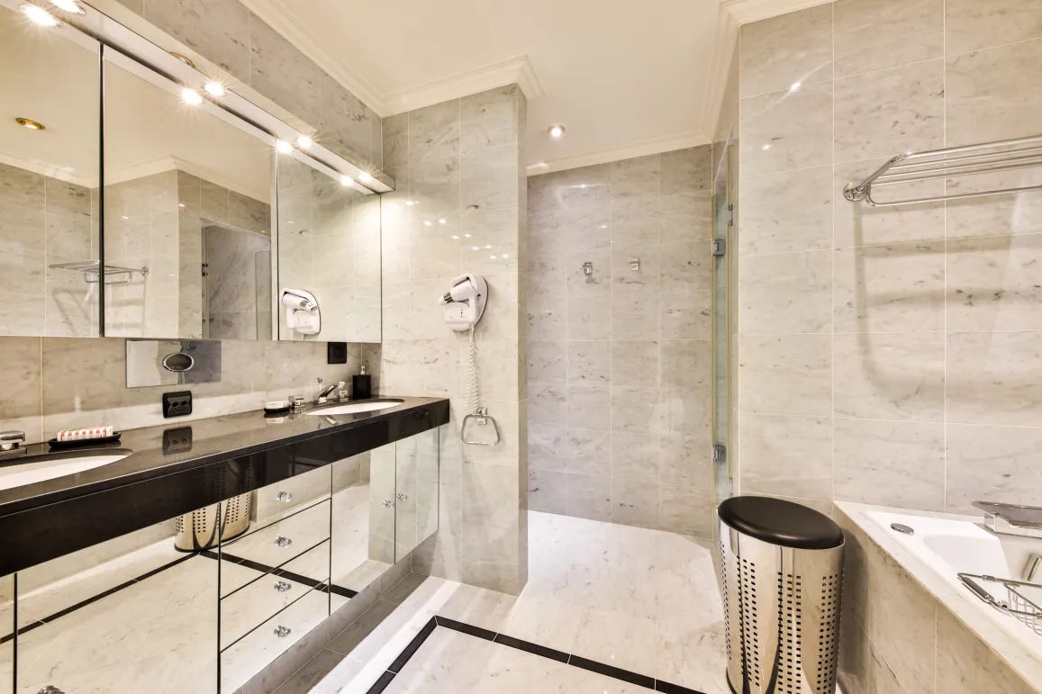 Salle de bain de luxe en marbre. Double vasque, miroir éclairé, douche et baignoire. Design moderne et élégant.