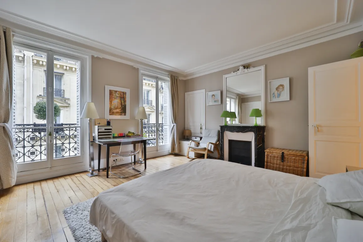 Chambre lumineuse style Haussmannien à Paris. Parquet, cheminée, balcon. Idéal appartement de luxe, charme et élégance.