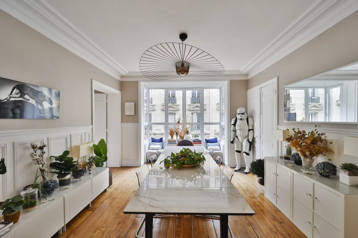 Salle à manger de luxe parisienne, design moderne et éclectique. Luminosité, parquet, moulures et vue ville. Un intérieur unique et raffiné.