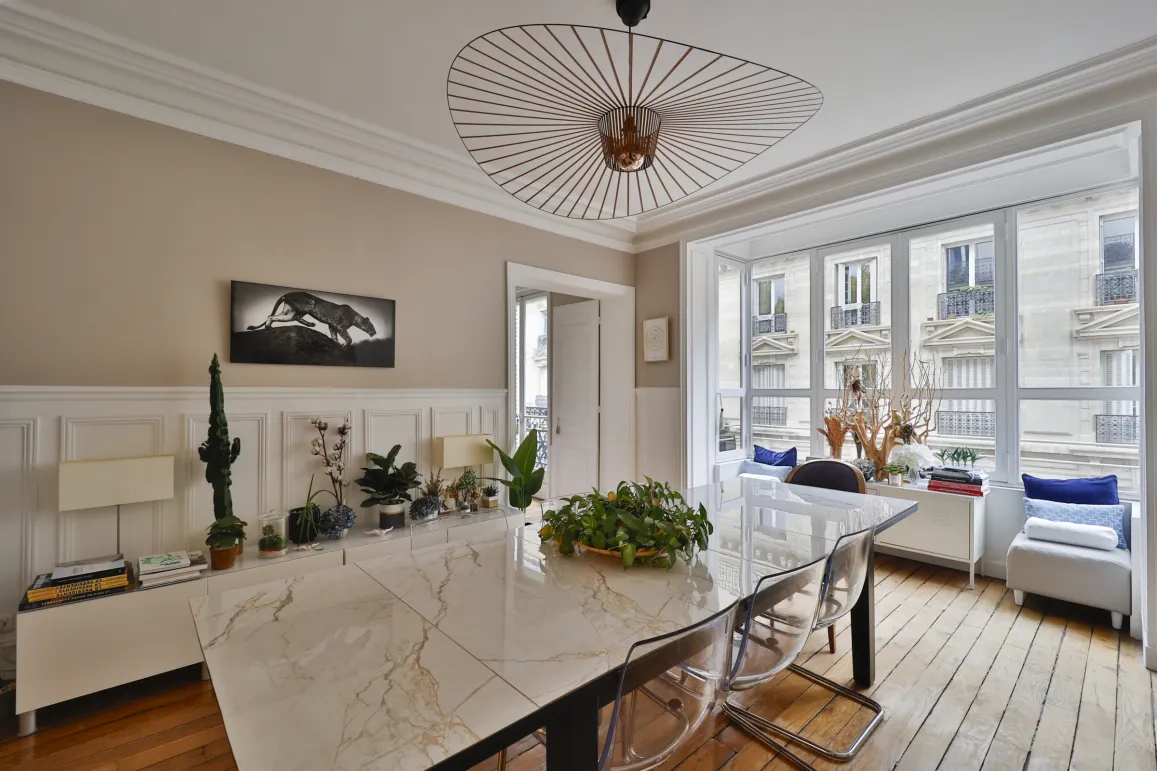 Salle à manger de luxe lumineuse à Paris. Design moderne élégant, grande table marbre, vue imprenable sur architecture haussmannienne.