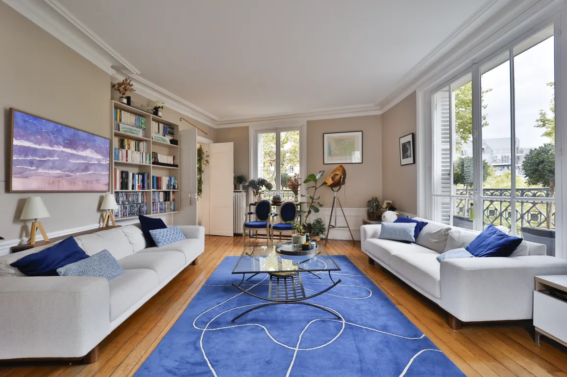 Appartement de luxe: salon spacieux et lumineux, design contemporain, parquet, canapés blancs, tapis bleu. Idéal pour vie urbaine élégante.