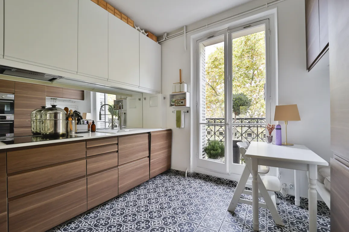 Cuisine de luxe moderne bois/blanc, sol carreaux ciment, balcon. Élégance et fonctionnalité pour appartement de prestige.