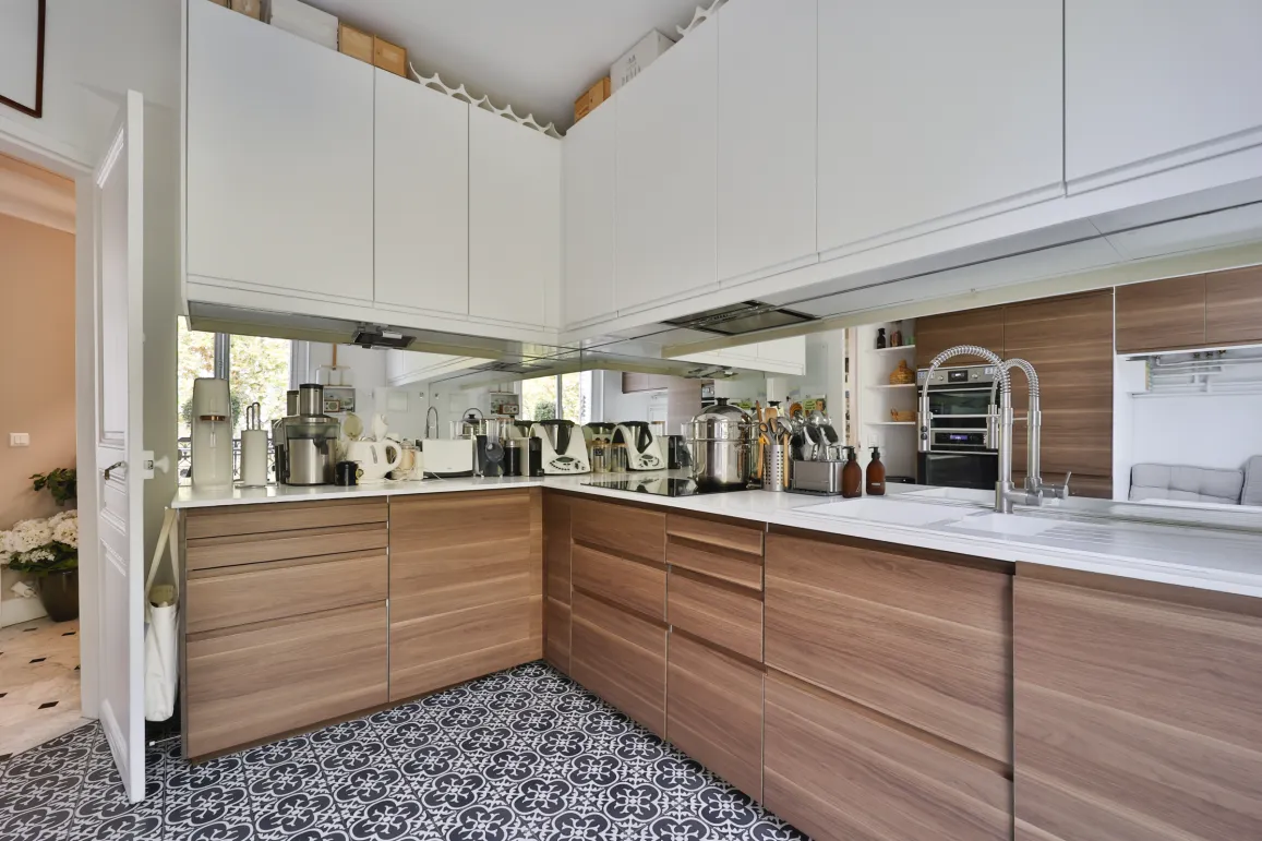 Cuisine de luxe moderne bois/blanc, carrelage design. Électroménager intégré, miroir mural. Espace fonctionnel et élégant pour vie contemporaine.