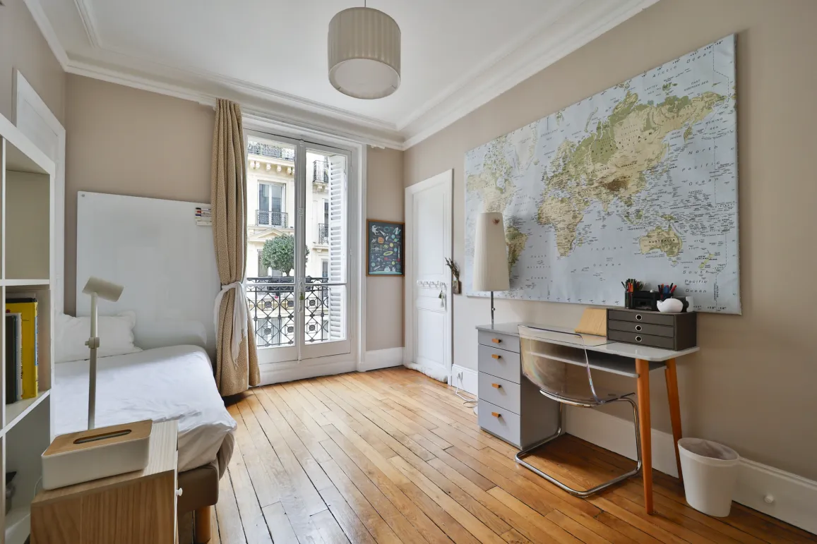 Chambre parisienne élégante, parquet, balcon, bureau. Idéal pour un pied-à-terre de luxe au cœur de Paris.