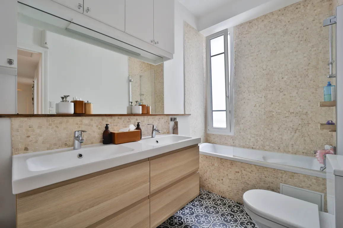 Design moderne pour cette salle de bain de luxe: double vasque, meuble bois, mosaïque murale, baignoire et sol carreaux de ciment. Ambiance raffinée.