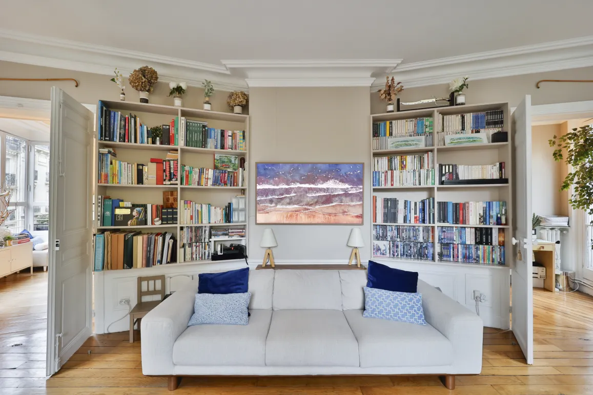 Salon de luxe élégant: canapé blanc, bibliothèques intégrées, œuvre d'art moderne. Ambiance raffinée pour intérieur haut de gamme.