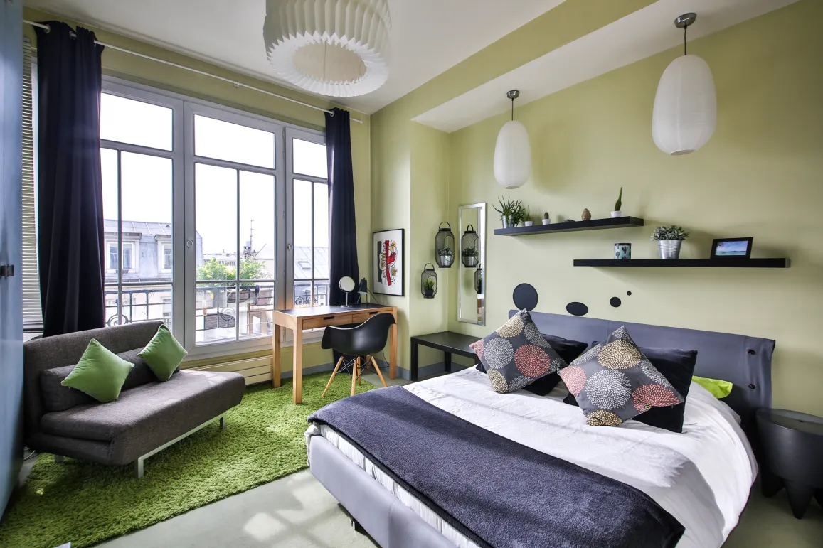 Chambre moderne et lumineuse avec vue ville, design contemporain, lit confortable, espace bureau et coin détente. Idéal appartement de luxe.