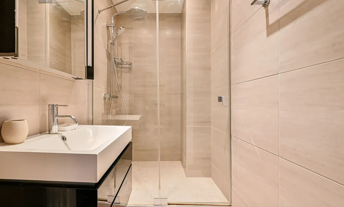 Salle de bain contemporaine: douche à l'italienne, lavabo design, carrelage clair. Ambiance zen et luxe pour propriété d'exception.