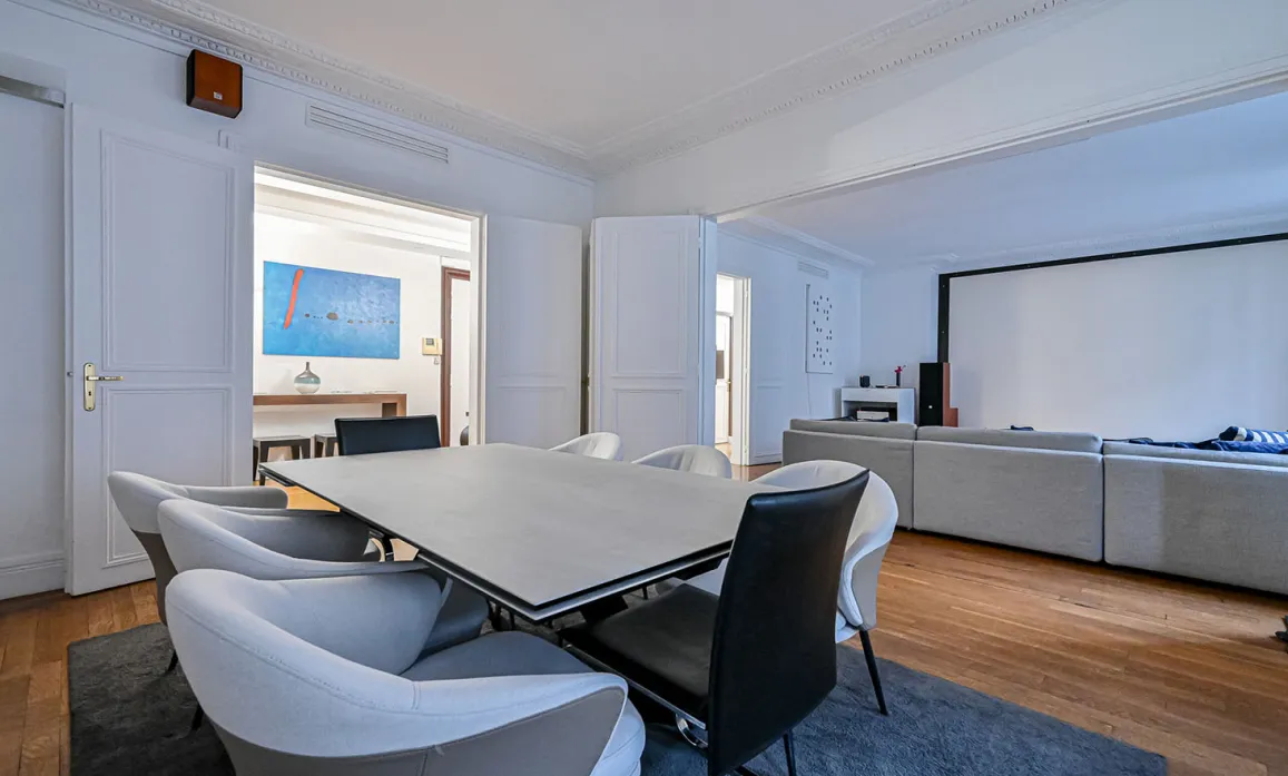 Salle à manger design ouverte sur salon home cinéma. Intérieur luxe moderne et spacieux avec parquet. Élégance et confort.
