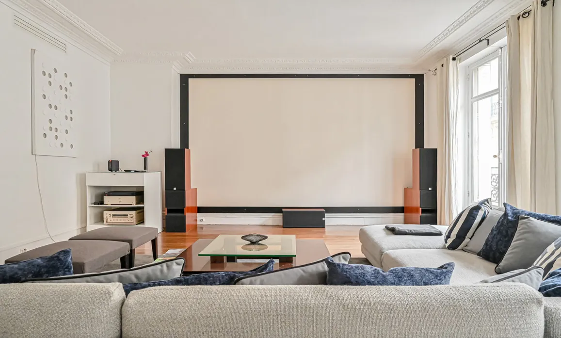 Salon de luxe avec home cinéma intégré, grand écran de projection, canapés confortables. Idéal pour divertissement haut de gamme et soirées film.
