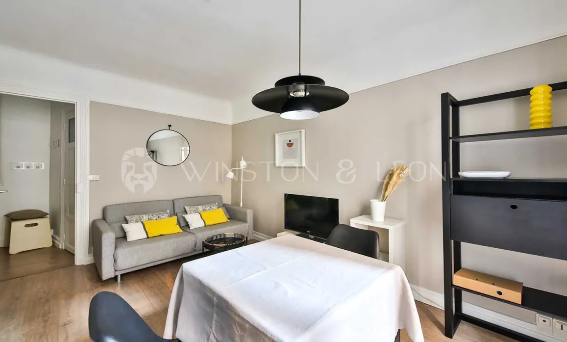Espace de vie moderne et lumineux: salon avec canapé gris, coussins jaunes, salle à manger épurée. Idéal pour un appartement de luxe.