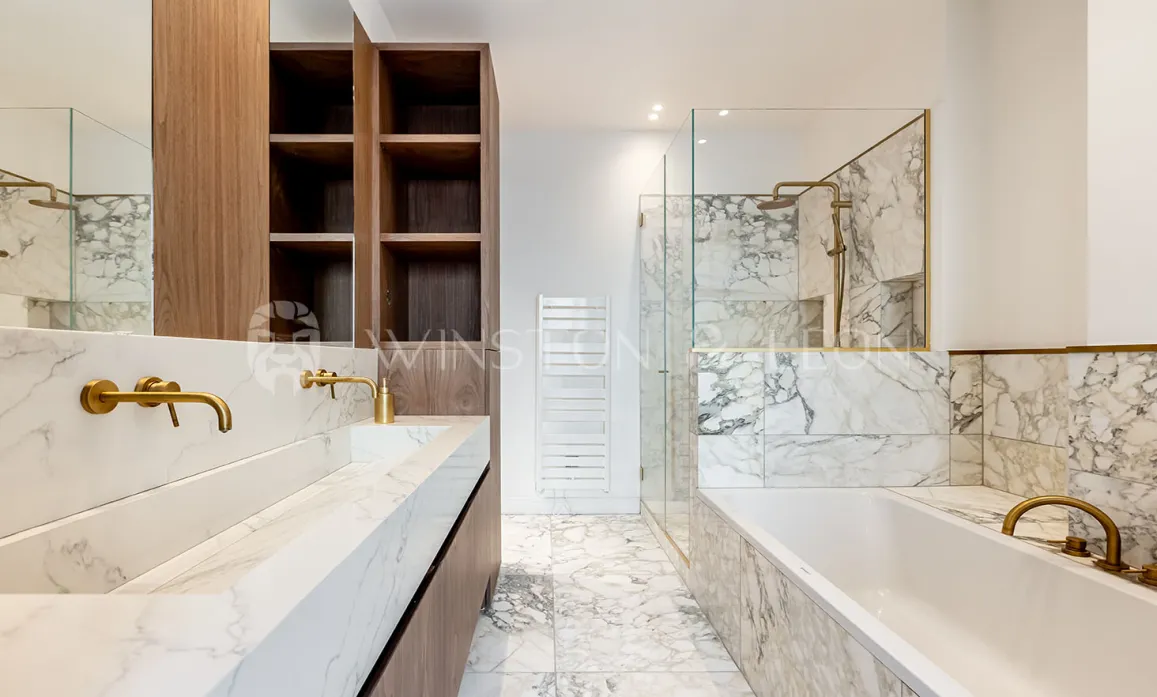 Salle de bain de luxe moderne : marbre blanc, double vasque, robinetterie dorée, douche à l'italienne et baignoire. Design élégant.