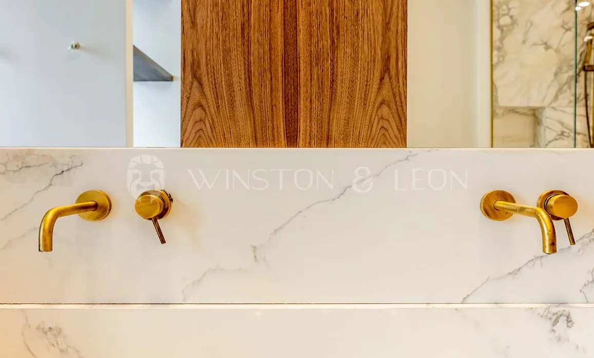 Salle de bain luxe: robinetterie laiton murale sur marbre blanc veiné. Design contemporain élégant. Winston & Leon.